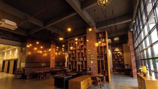 A spacious library with high ceilings, exposed brick walls, and multiple reading areas with bookshelves and seating. - Zhehui Hotel (Zhongshan)