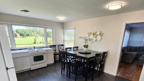 Une cuisine moderne avec un coin repas, de grandes fenêtres et une vue sur l’extérieur.
