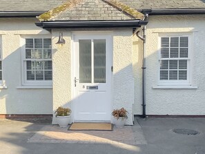 A white house with a number 5 on the door, two potted plants, and a doormat. - The Guards Quarters - UK47594 (Silloth)