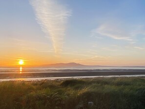 A sunset over a beach with grassy dunes in the foreground. - The Guards Quarters - UK47594 (Silloth)