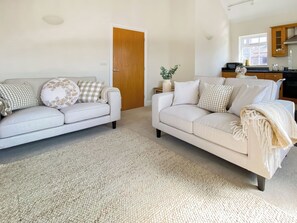 Ein Wohnzimmer mit zwei Sofas, einem Teppich und einer Küche im Hintergrund.