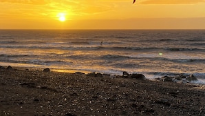A beach at sunset with a kite surfer in the distance.