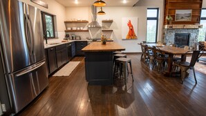 A modern kitchen with stainless steel appliances, a central island, and a dining area with wooden furniture.