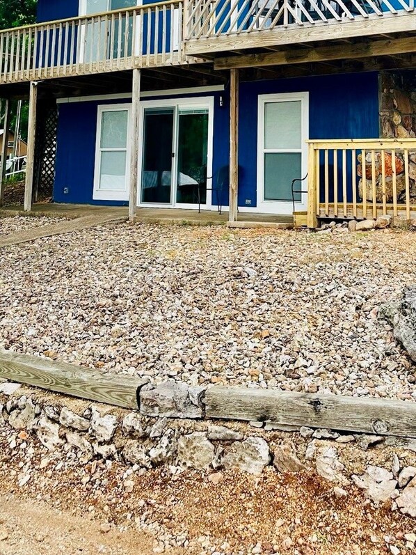 A building with a blue exterior, a wooden deck, and a gravel driveway.