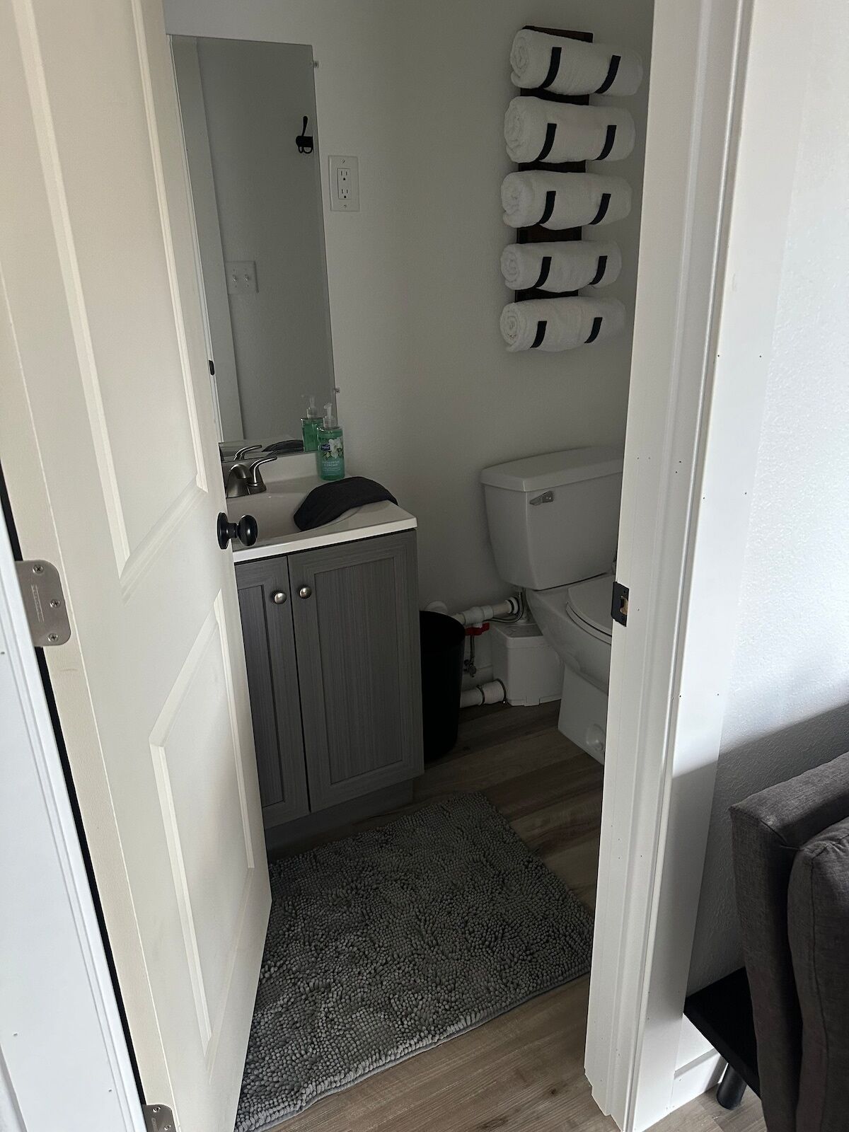 A bathroom with a toilet, sink, mirror, and towel rack.