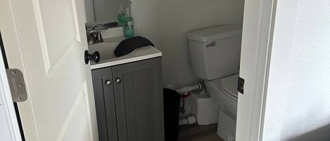 A bathroom with a toilet, sink, mirror, and towel rack.