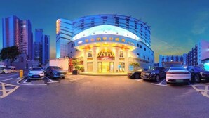 A hotel with a curved facade, multiple floors, and a prominent entrance with illuminated signage. - Vienna Classic Hotel (Shenzhen MixC Mall) (Shenzhen)