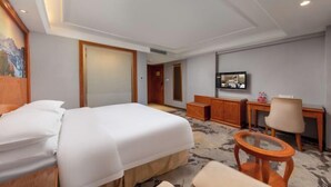 A hotel room with a bed, a desk, a chair, a television, and a painting on the wall. - Vienna Classic Hotel (Shenzhen MixC Mall) (Shenzhen)