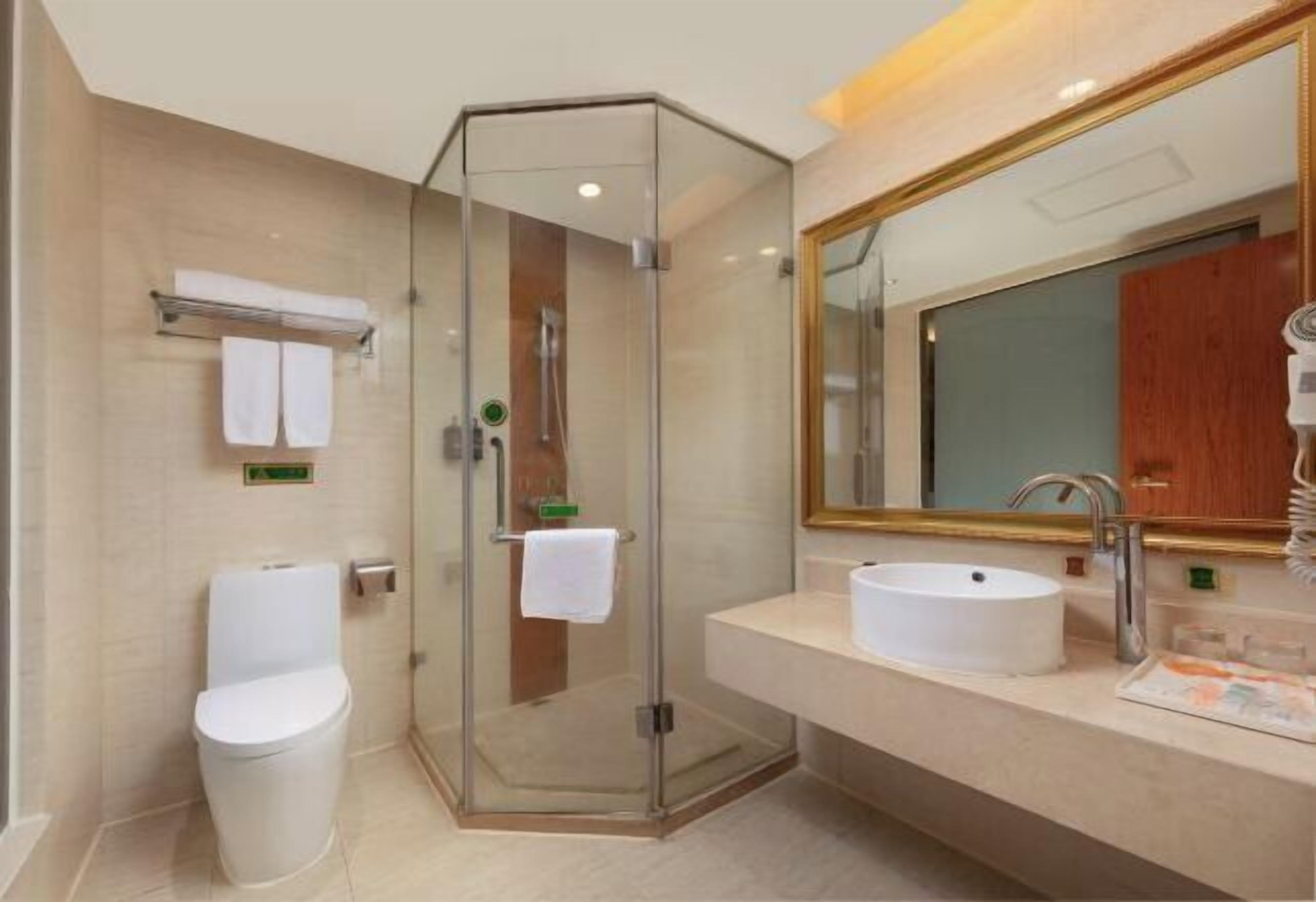 Une salle de bain moderne avec une douche à parois de verre, un lavabo blanc et un grand miroir.