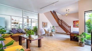 A spacious living area with a wooden staircase, a sofa set, and various plants. - Bakong Hotel (Siem Reap)