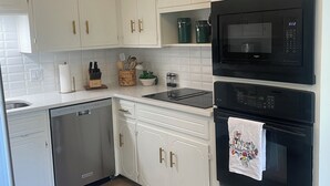 Una cocina moderna con armarios blancos, un microondas negro y un lavavajillas.