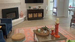 Una sala de estar con chimenea, un televisor de pantalla plana y una zona de comedor con mesa y sillas.