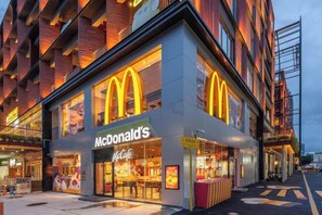 Um restaurante McDonald's com fachada moderna, grandes janelas e entrada para atendimento direto.