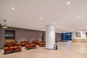 Um hall amplo com teto alto, piso de madeira e uma coluna central.
