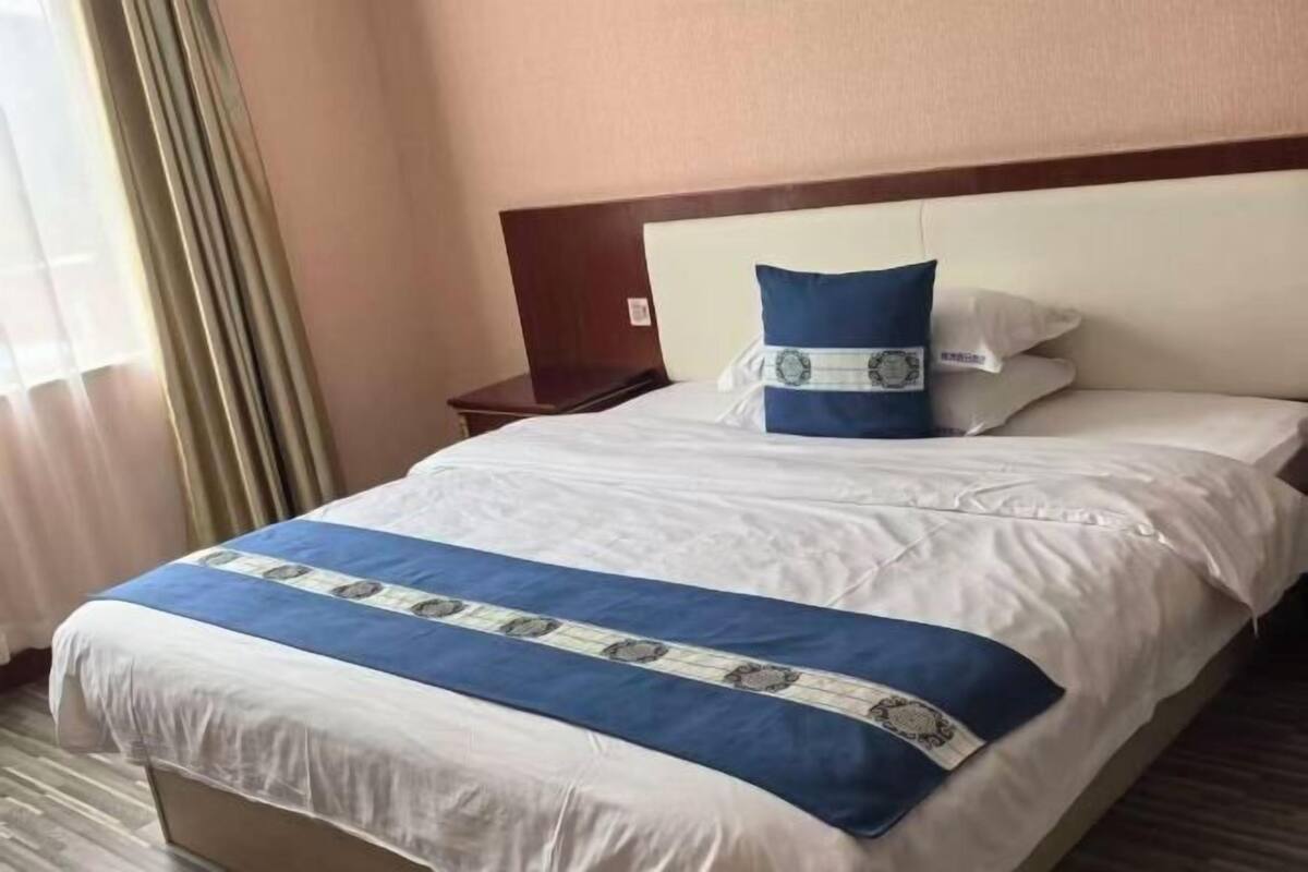 Une chambre d’hôtel avec un grand lit, une tête de lit en bois et une table de chevet avec une lampe.