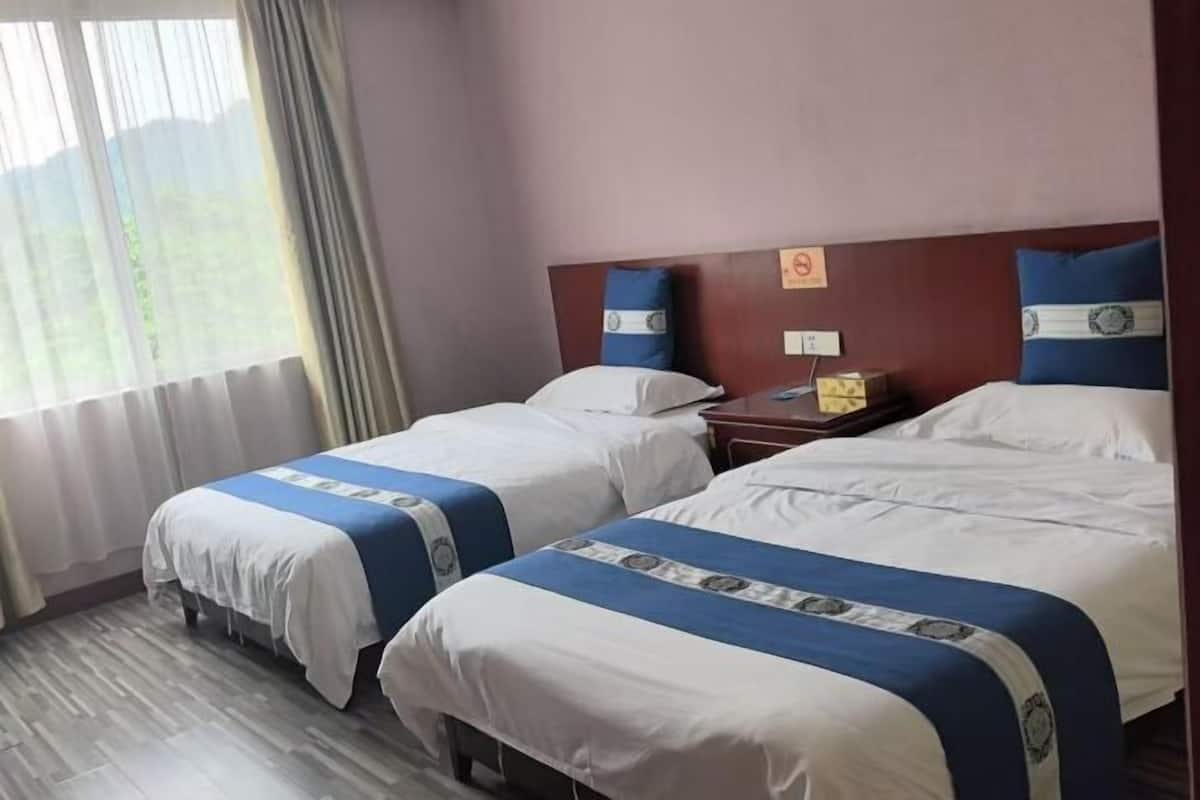 Une chambre d’hôtel avec deux lits, une table de chevet et une fenêtre avec des rideaux.