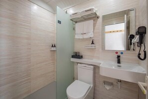 A modern bathroom with a toilet, sink, mirror, and hairdryer.