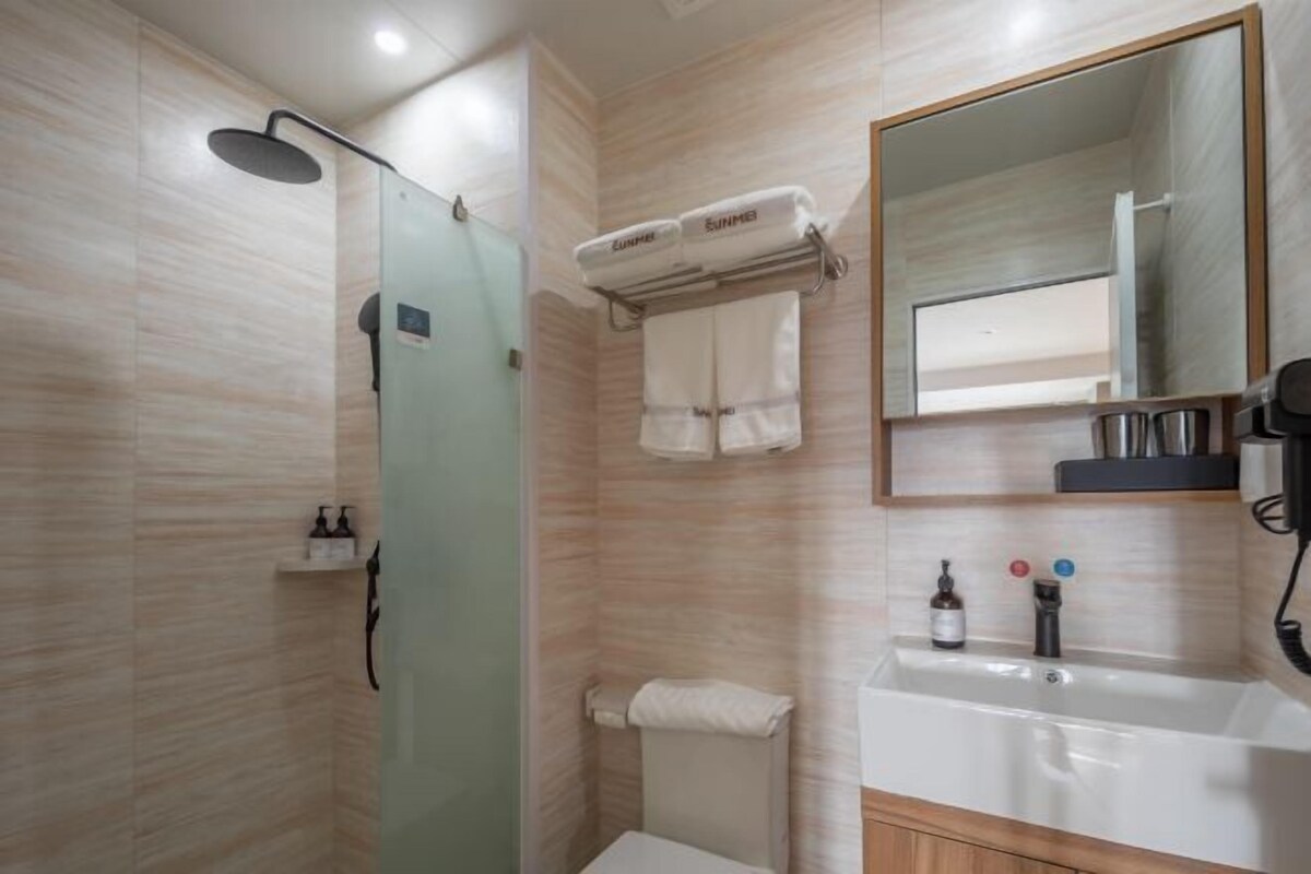A modern bathroom with a glass-enclosed shower, a sink with a mirror, and a towel rack.