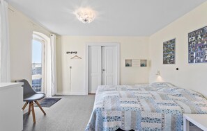Un dormitorio con una cama, un escritorio, una silla, una puerta y una ventana.