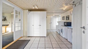 Een moderne keuken met witte kasten, een magnetron en een wasmachine.