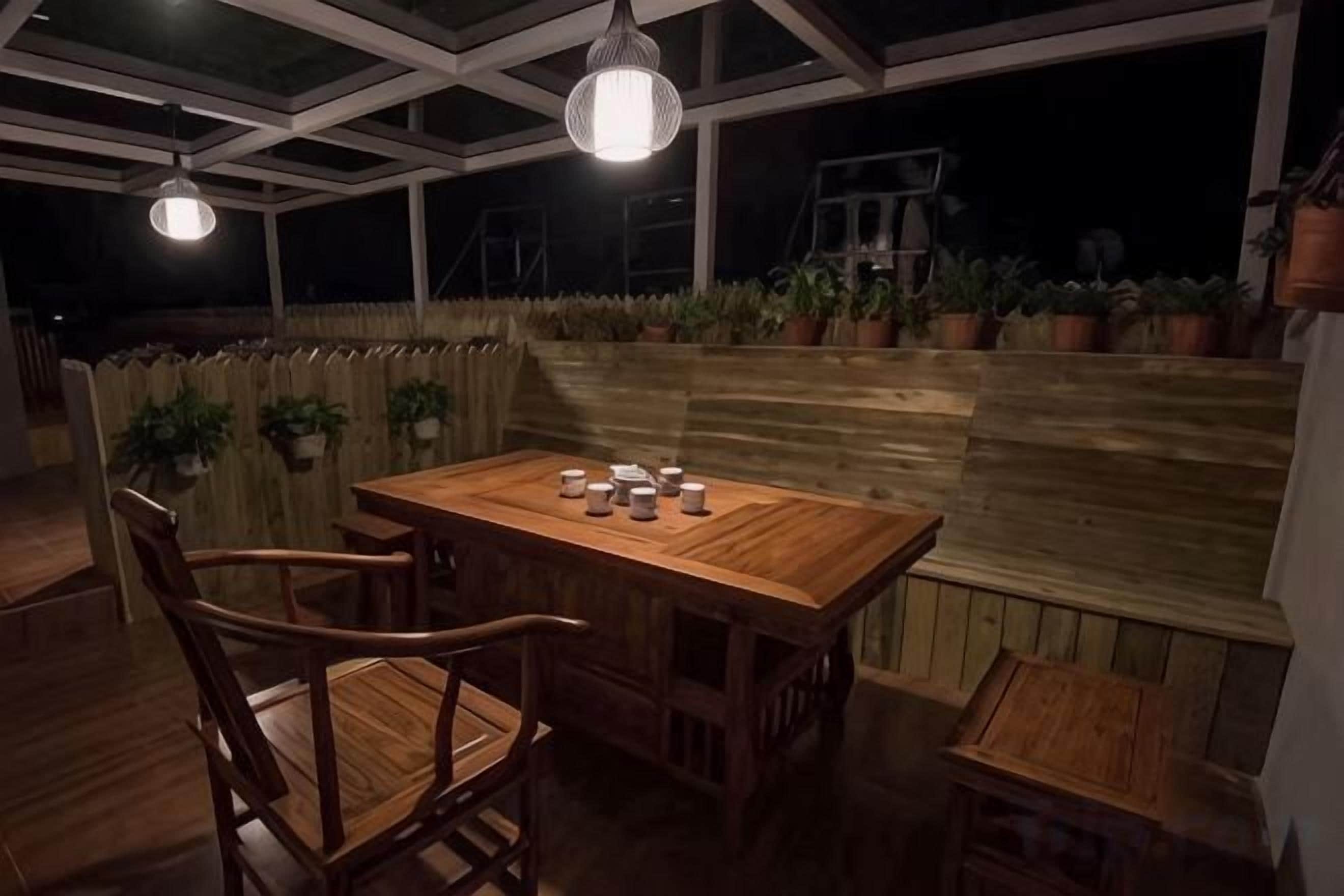 An outdoor dining area with a wooden table and chairs, surrounded by potted plants.