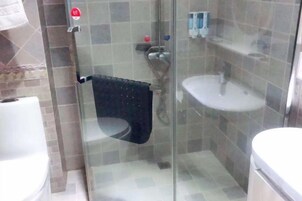 Un área de ducha con paredes de vidrio, un lavabo blanco y un perchero para toallas.