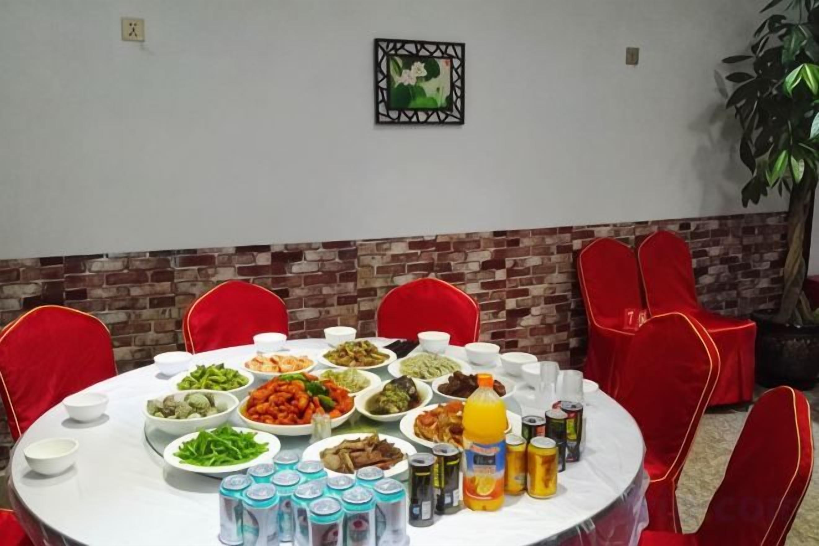A round table with various dishes and drinks, surrounded by red chairs.