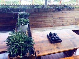 Un banco de madera con macetas, una mesa con tetera y una barandilla de madera con plantas.