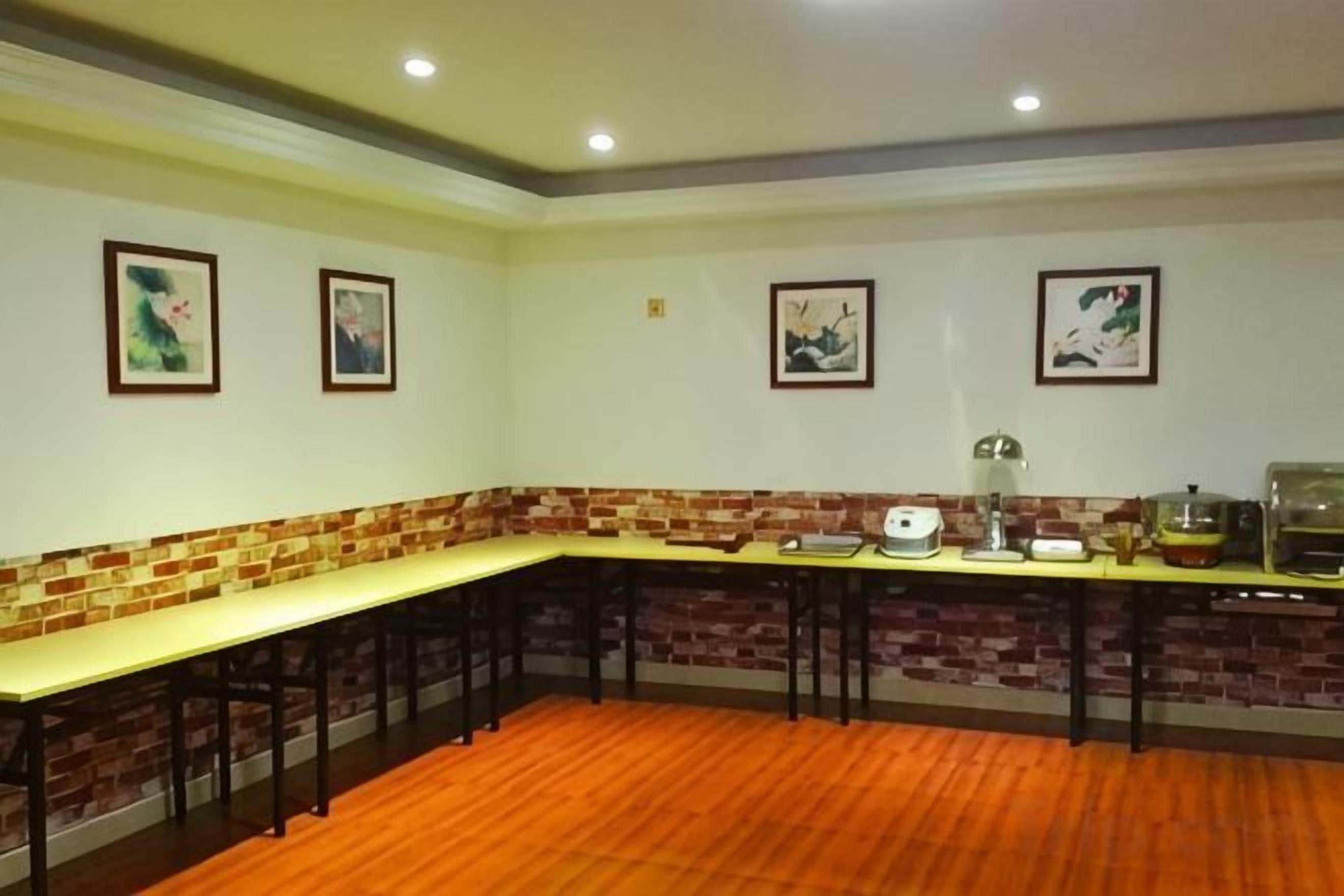 Una habitación con una mesa larga, sillas, una pared de ladrillo decorativa y cuadros en la pared.