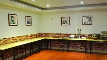 Una habitación con una mesa larga, sillas, una pared de ladrillo decorativa y cuadros en la pared.
