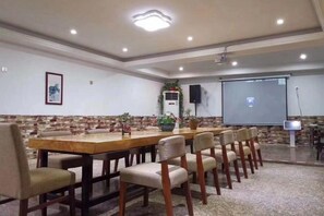 A conference room with a long table, chairs, a projector screen, and a speaker. - Yujian Duxiulou Hotel (Yueqing)