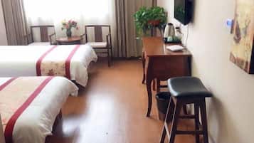 Habitación de hotel con dos camas, un escritorio, una silla, un televisor y una planta.