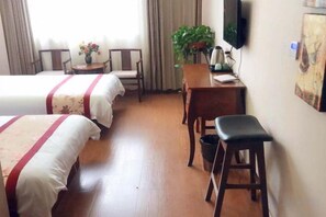 A hotel room with two beds, a desk, a chair, a television, and a plant. - Yujian Duxiulou Hotel (Yueqing)