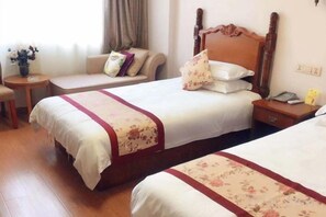 Ein Hotelzimmer mit zwei Betten, einem Schlafsofa, einem kleinen Tisch und einem Nachttisch.