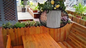A wooden bench with a hanging planter containing flowers and a decorative item.