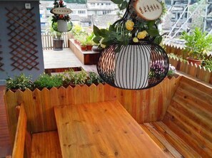 A wooden bench with a hanging planter containing flowers and a decorative item.