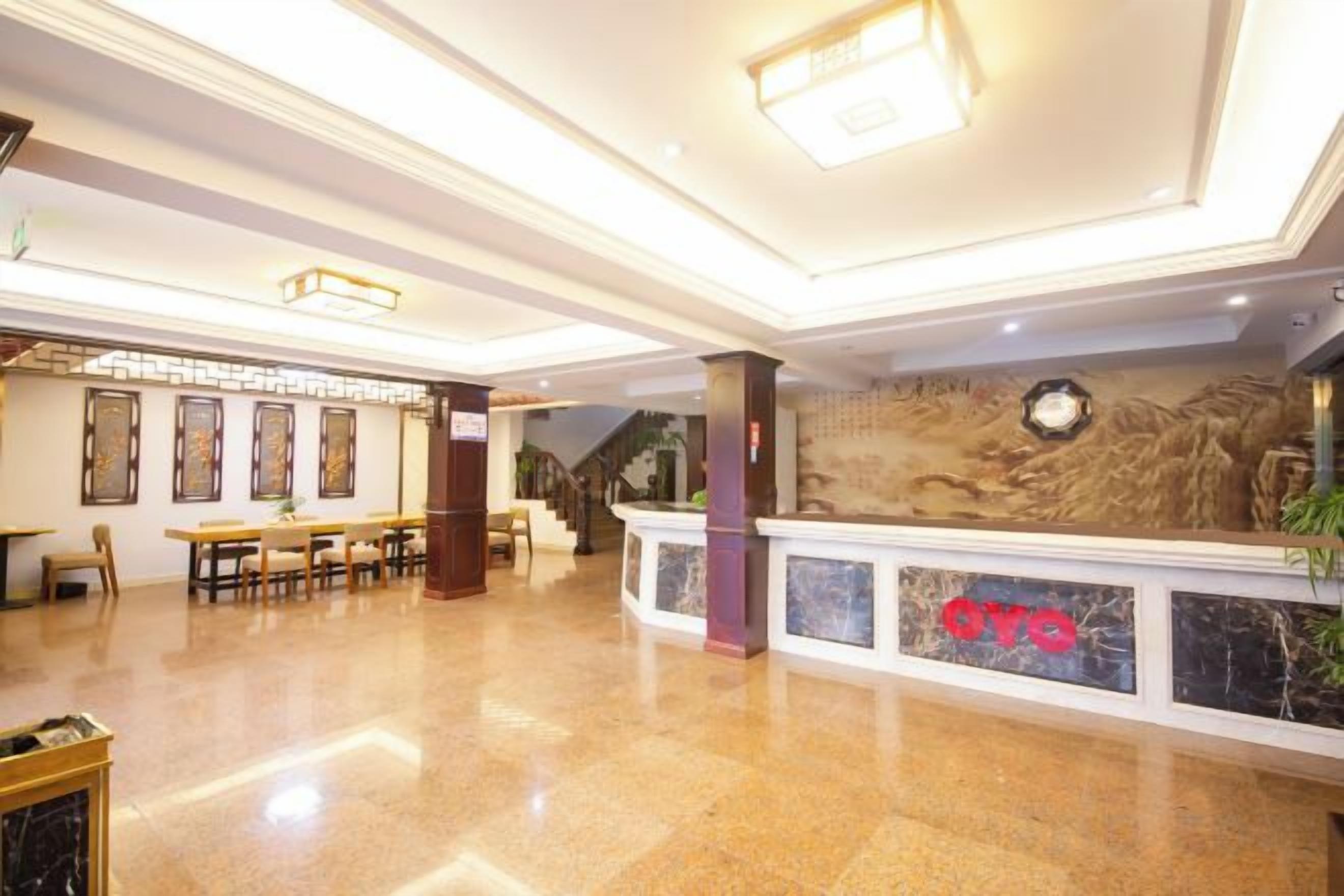 Un vestíbulo amplio con mostrador de recepción, zona de estar y una escalera.