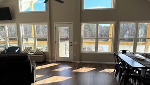 Un espacio habitable amplio con techo alto, ventanas grandes y una mesa de comedor.