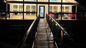 Un edificio grande y moderno con una terraza de madera que lleva a un acceso cubierto.