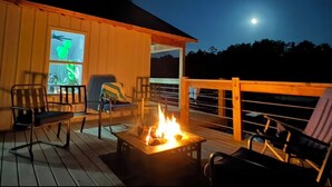Una terraza con una fogata, asientos exteriores y vistas al cielo nocturno.
