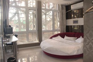 Une chambre avec une grande fenêtre, un lit, un bureau et une chaise.