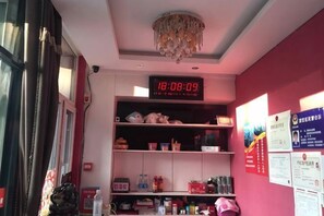 A room with a digital clock, shelves with various items, and a chandelier.