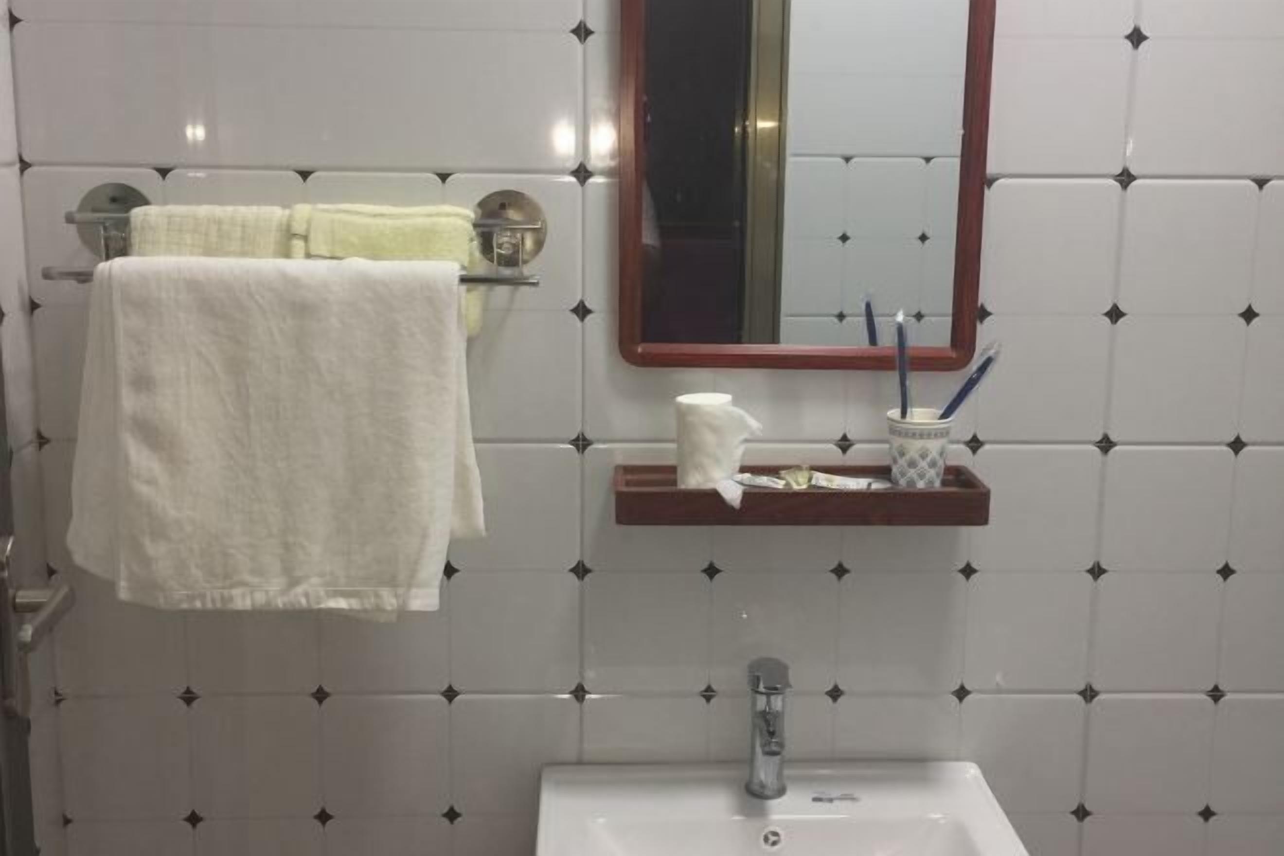 A bathroom with a white sink, a mirror, and a towel rack with two towels.