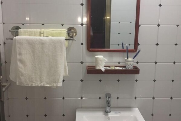 A bathroom with a white sink, a mirror, and a towel rack with two towels. - Shenyang Jiayi Theme Hotel (Shenyang)