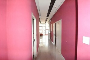 Un couloir aux murs roses, aux portes blanches et au sol carrelé.