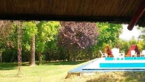 Ein Poolbereich mit einem Boot, umgeben von Bäumen und einer Rasenfläche.