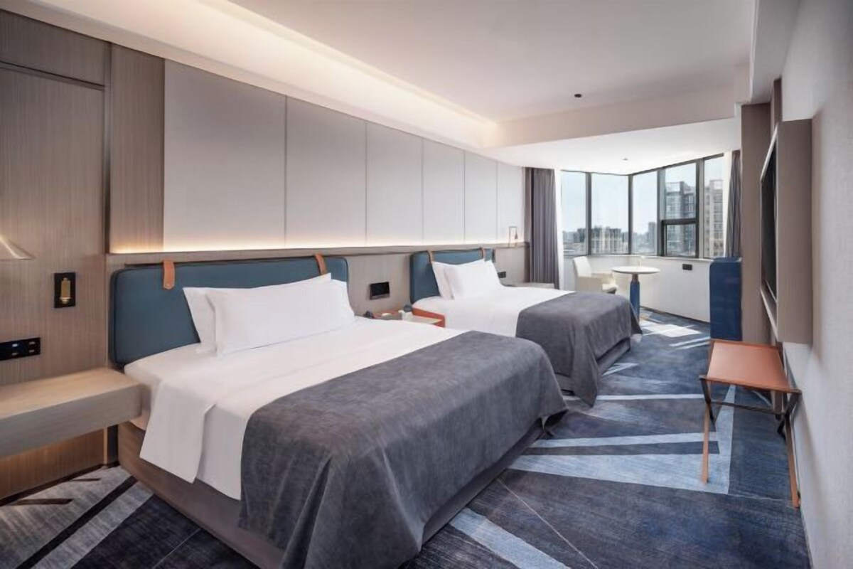 Une chambre d’hôtel avec deux lits, un bureau et une grande fenêtre.