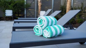 Une rangée de chaises longues, avec une paire de serviettes enroulées posées sur l’une d’elles.