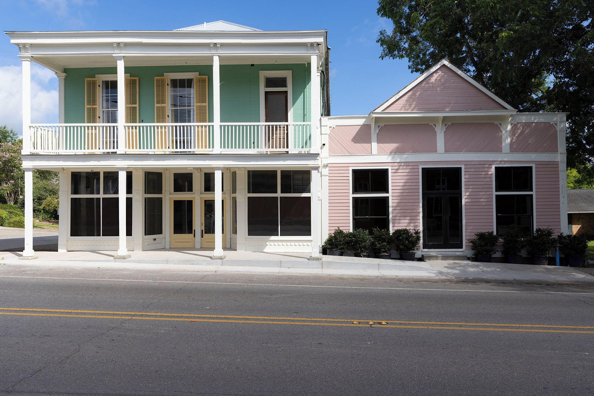 A two-story building with a balcony on the upper floor and a separate entrance with a porch.