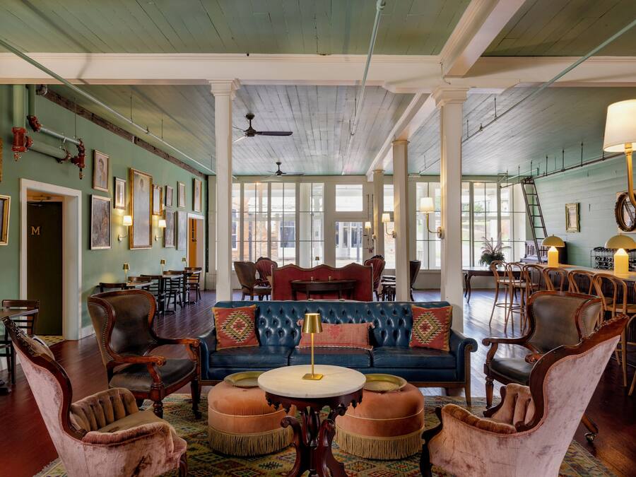 A spacious room with a blue sofa, leather armchairs, and a round table.